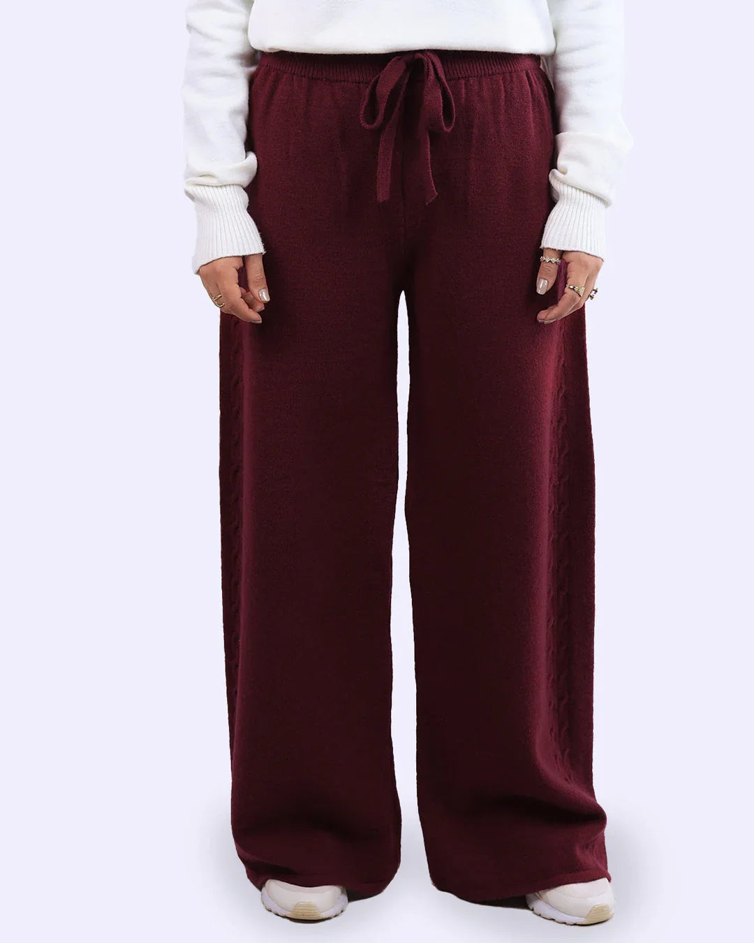 Woman wearing burgundy wide-leg knit pants with drawstring, white sweater and sneakers