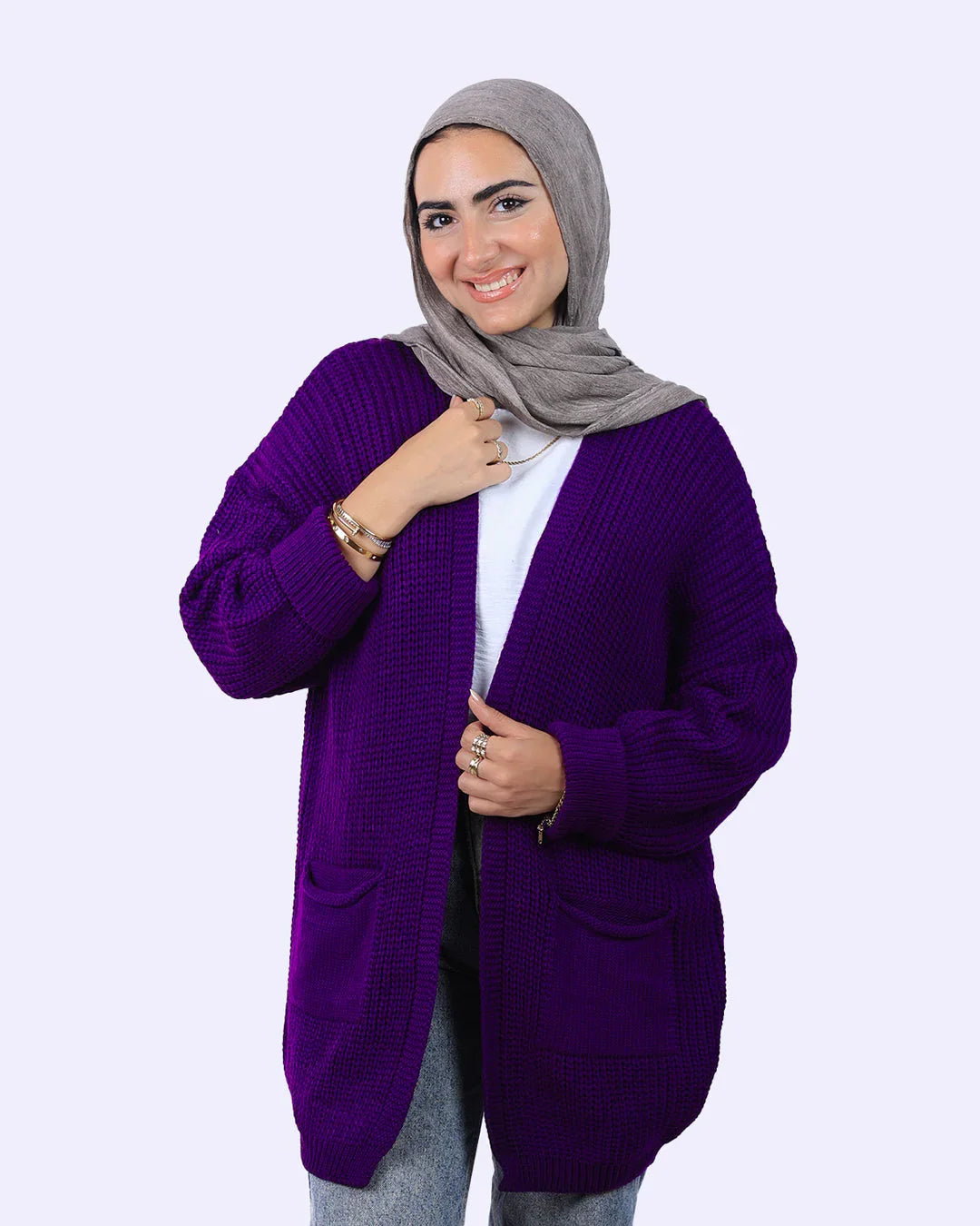 Smiling woman in grey hijab and purple knit cardigan from WIND Shopping, modern fashion.