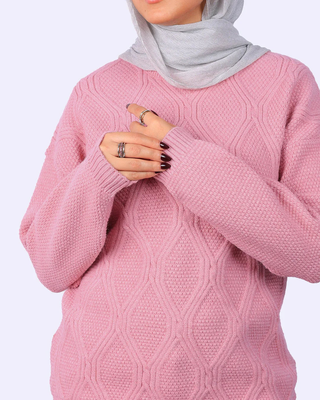 Woman wearing a light grey hijab and textured pink sweater with rings, WIND Shopping fashion.
