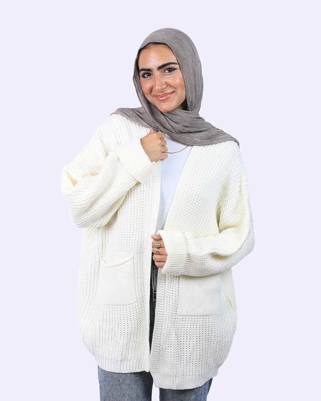 Woman in light gray hijab and cream knit cardigan from WIND Shopping, smiling against plain background