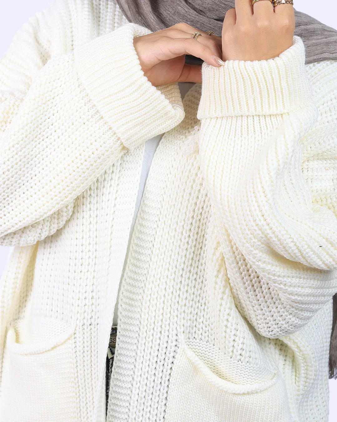 Woman wearing cream knit cardigan and gray scarf, showcasing WIND Shopping fashion in Egypt