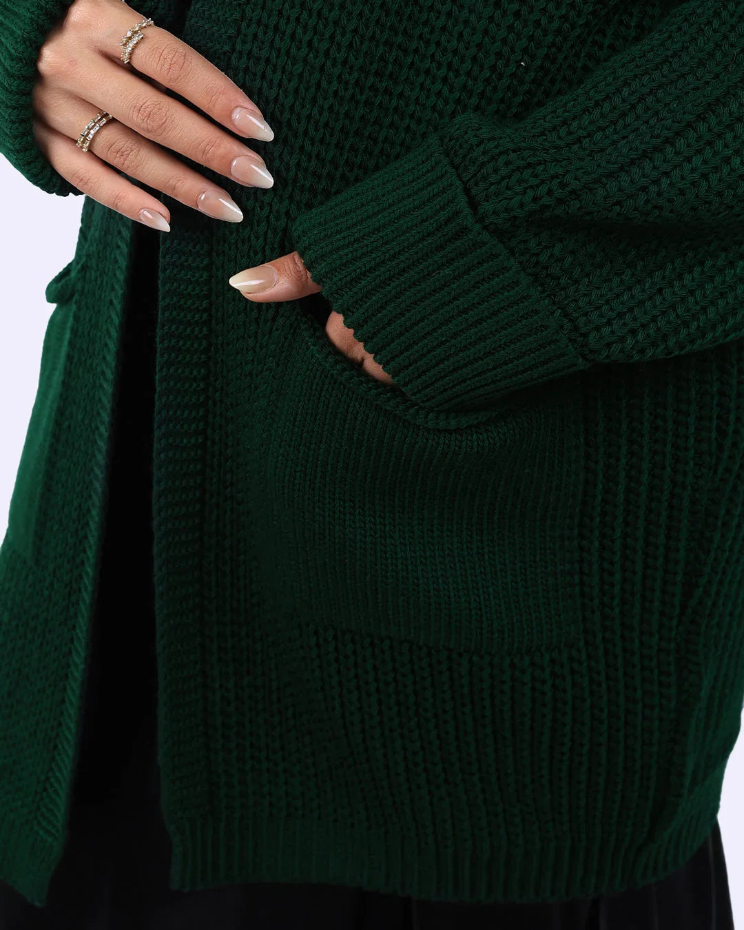 Close-up of a hand in pocket of dark green knit cardigan from WIND Shopping fashion collection