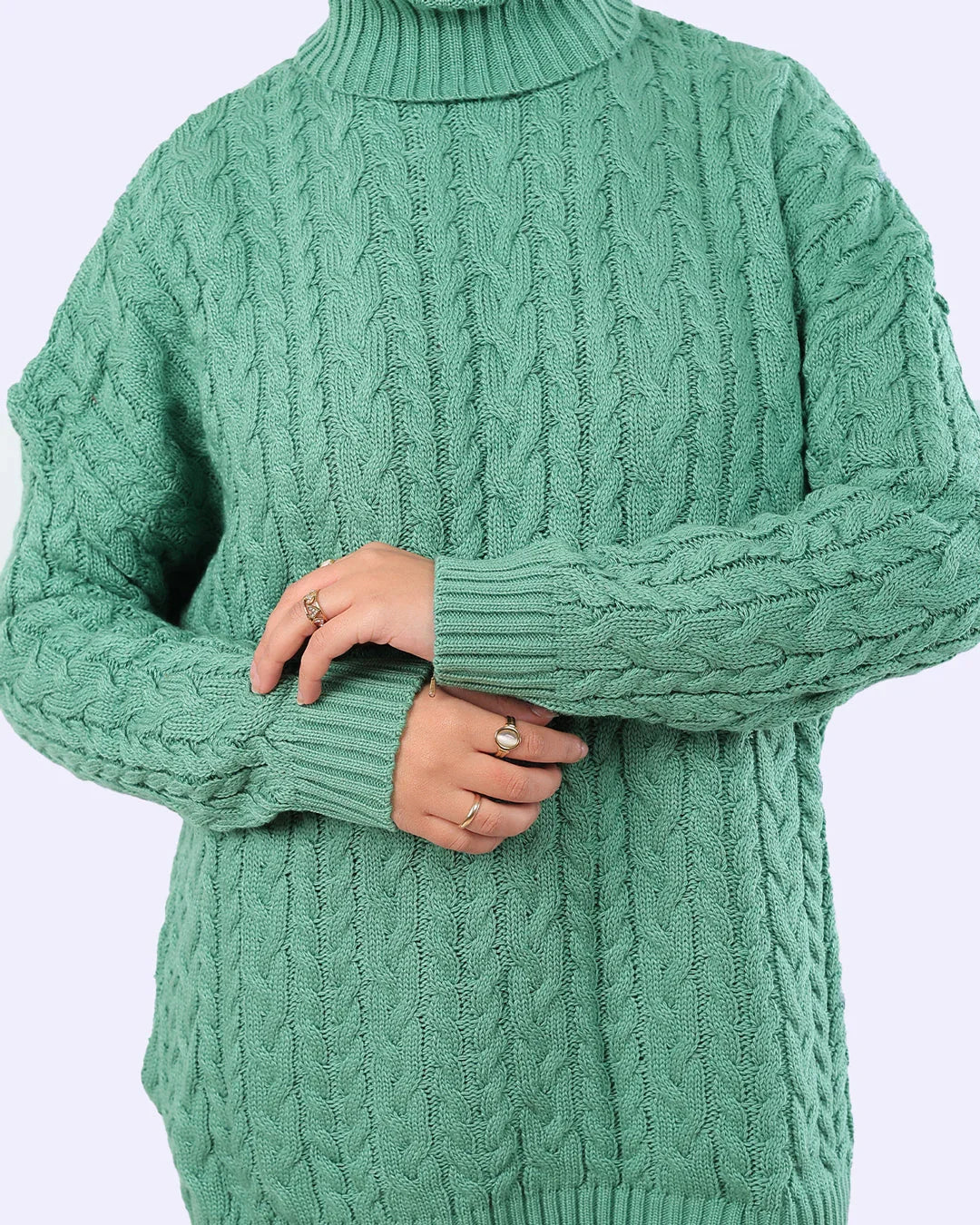 Woman wearing a green cable knit sweater from WIND Shopping, showing elegant winter fashion.