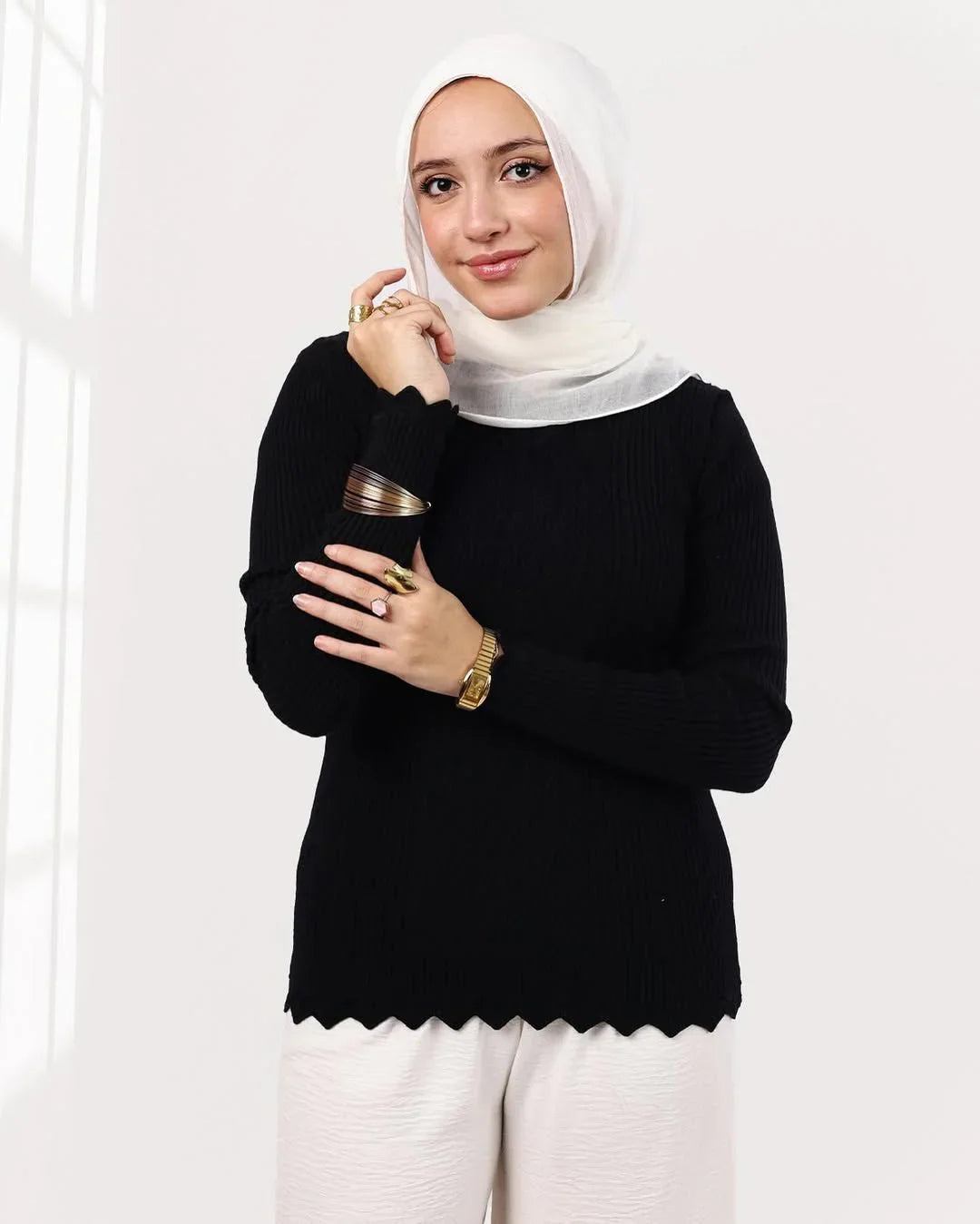 Woman wearing white hijab and black ribbed top from WIND Shopping, posing indoors in natural light.