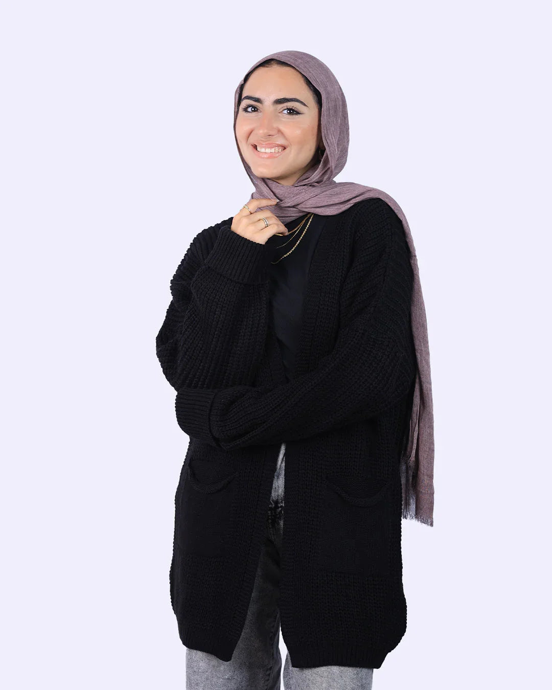Smiling woman in taupe hijab, black knit cardigan, and gray jeans from WIND Shopping