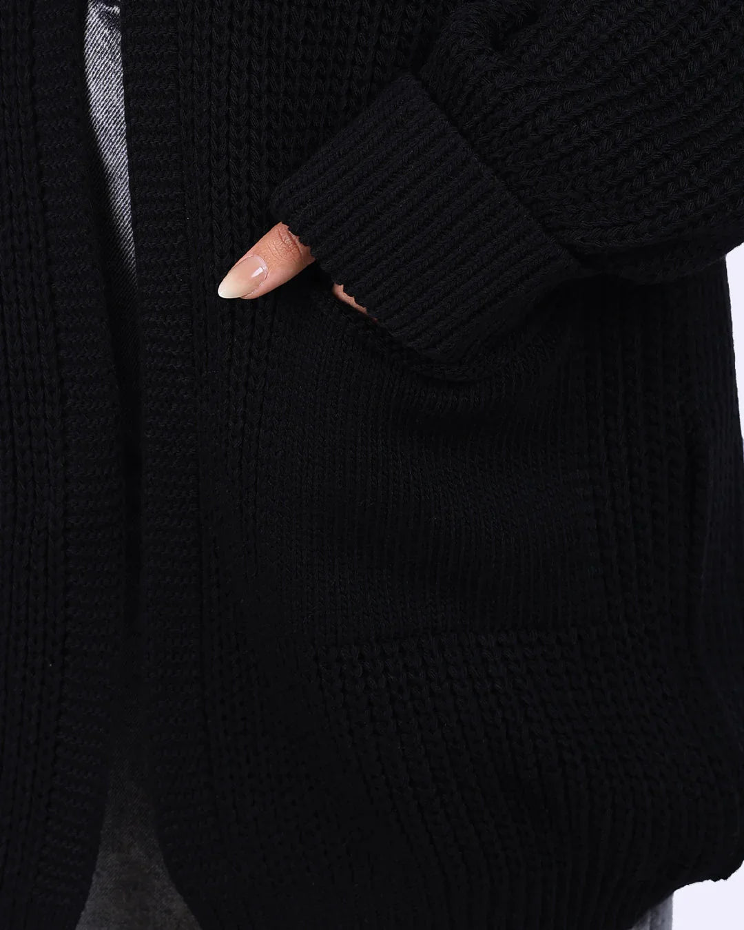 Close-up of a hand in the pocket of a black knit cardigan from WIND Shopping Egypt
