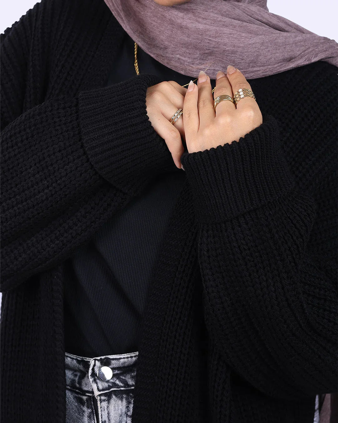 Woman wearing black textured cardigan, grey hijab, silver jeans, and gold rings from WIND Shopping
