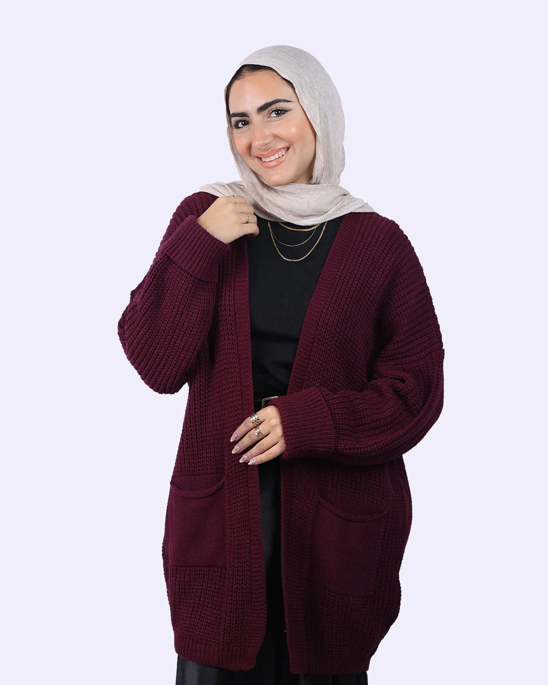 Woman in beige hijab and maroon knit cardigan from WIND Shopping, smiling on plain background