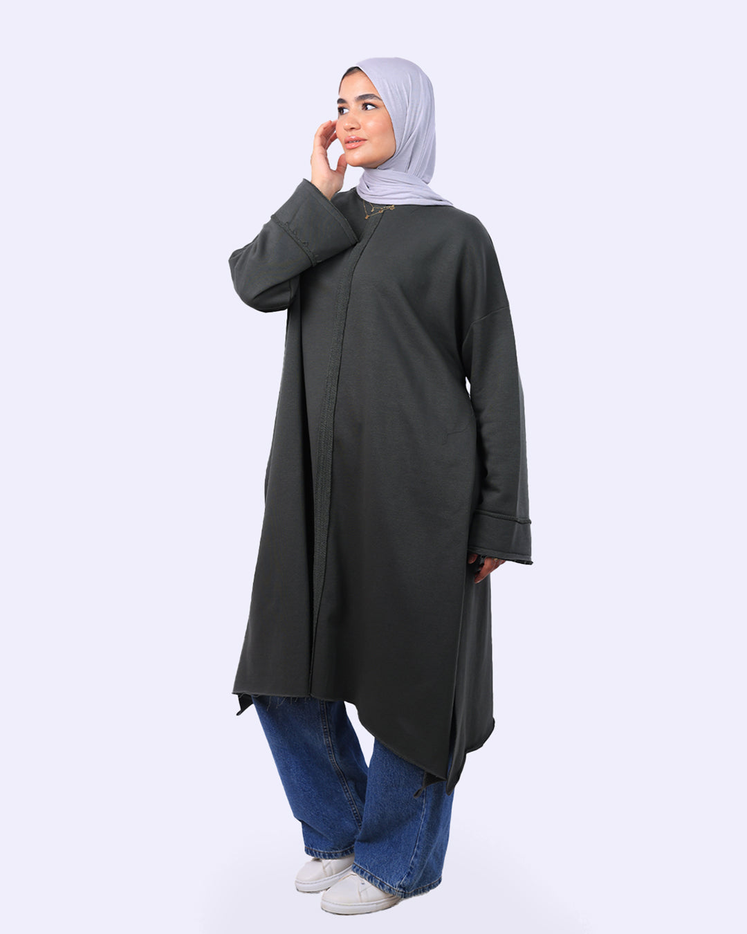 Woman wearing a long dark gray coat and blue jeans on a white background