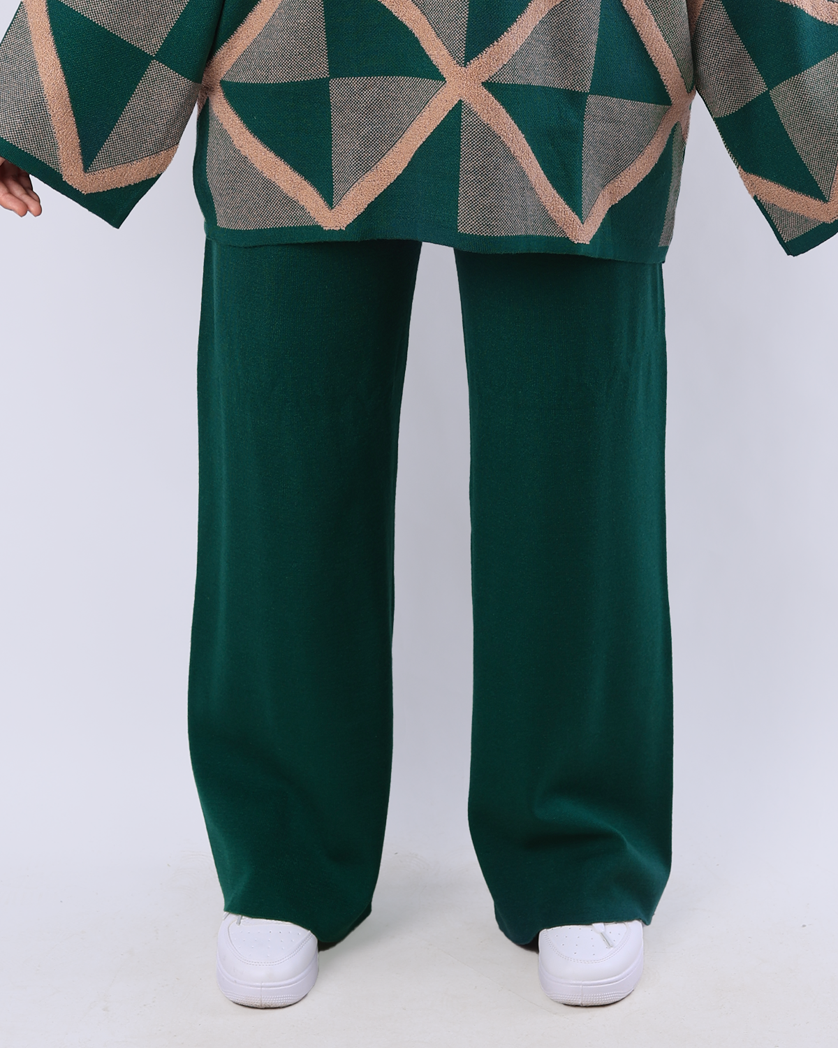 Green geometric-patterned sweater and wide-leg pants with white shoes on a light gray background