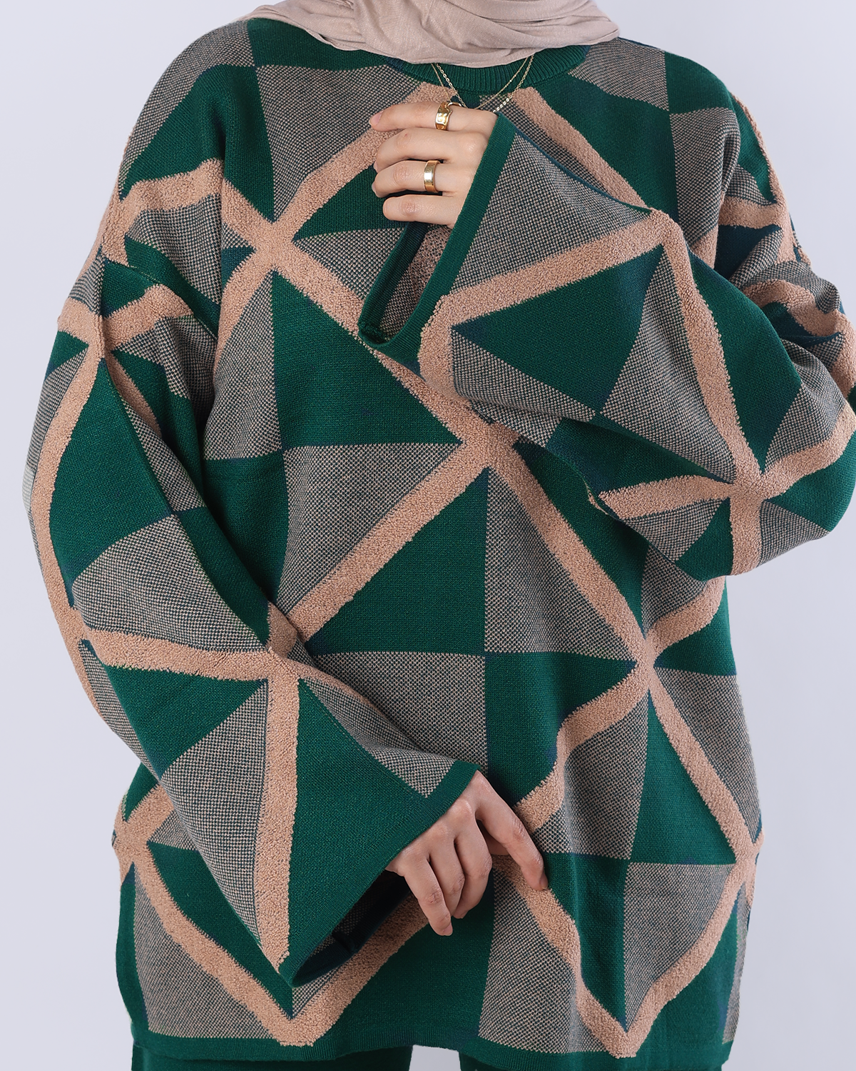 Person wearing a green and beige geometric patterned sweater on a white background
