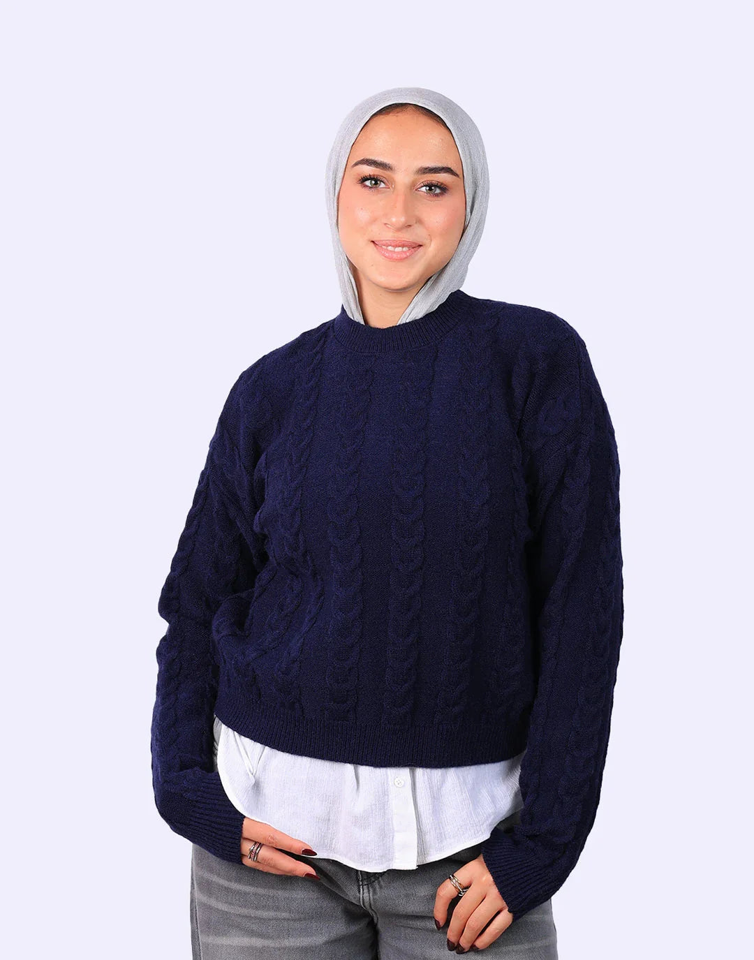 Woman in navy cable knit sweater, white shirt, gray hijab, and gray jeans from WIND Shopping