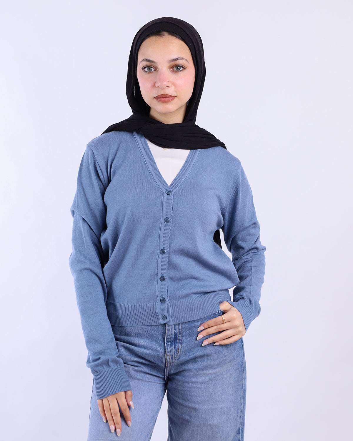 Woman wearing a blue cardigan and jeans with a black hijab on a white background-WIND Shopping