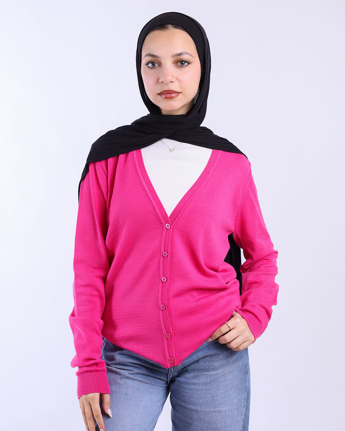 Person wearing a bright pink cardigan over a white shirt with a black hijab on a white background- WIND Shopping
