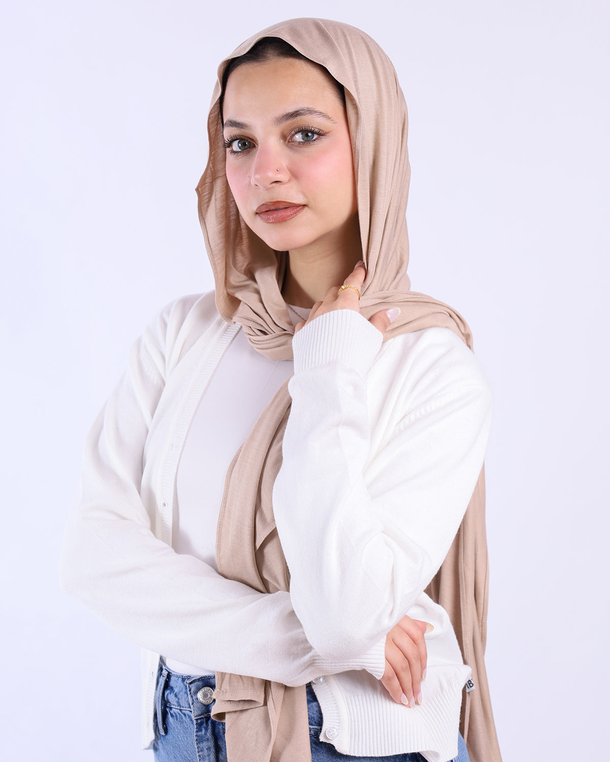 Woman wearing a beige hijab and white sweater on a light gray background-WIND Shopping
