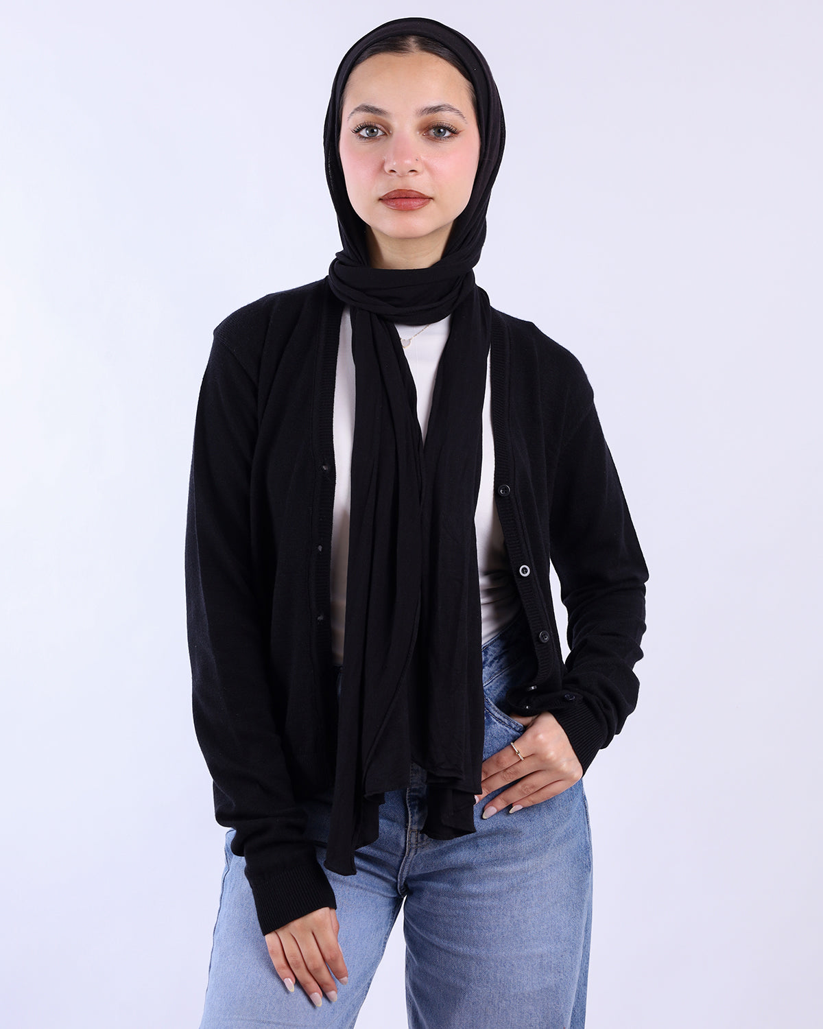 Person wearing a black hijab, black shirt, and blue jeans on a white background-WIND Shopping