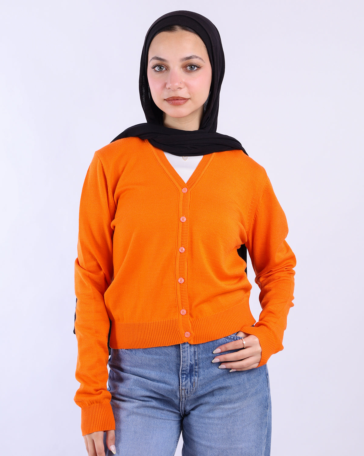 Person wearing an orange cardigan and black hijab on a white background- WIND Shopping