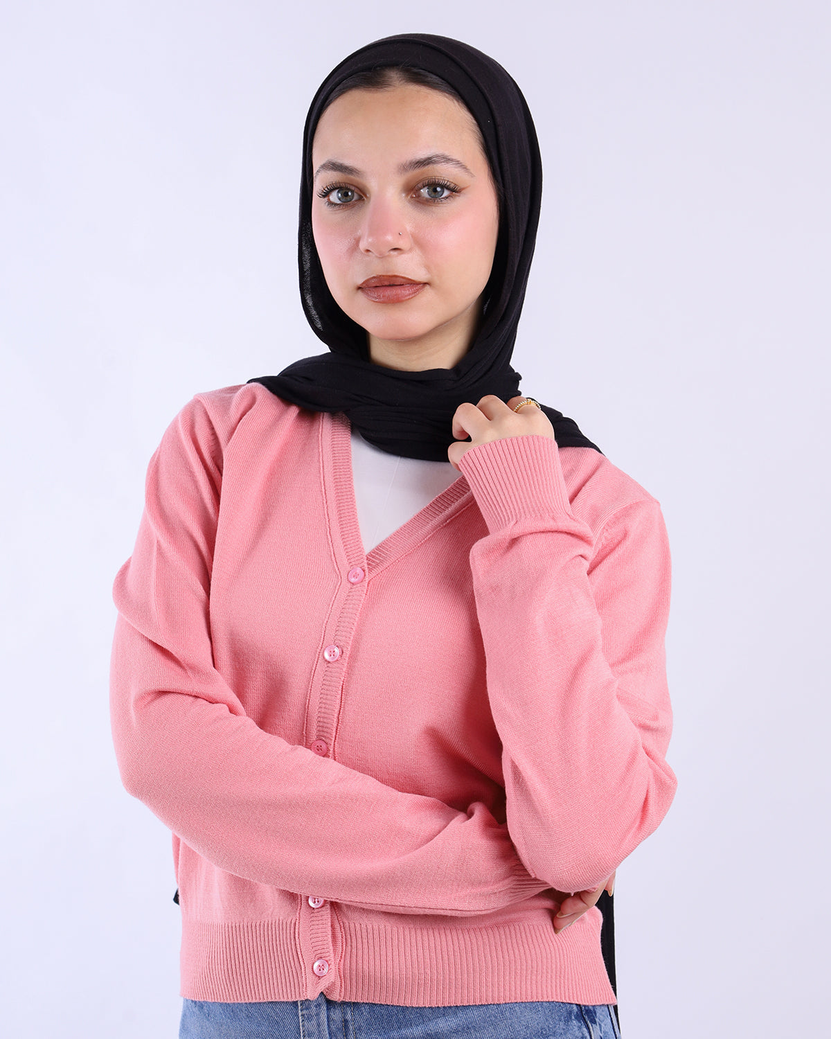 Woman wearing a pink cardigan over a white shirt with a black hijab on a white background-WIND Shopping