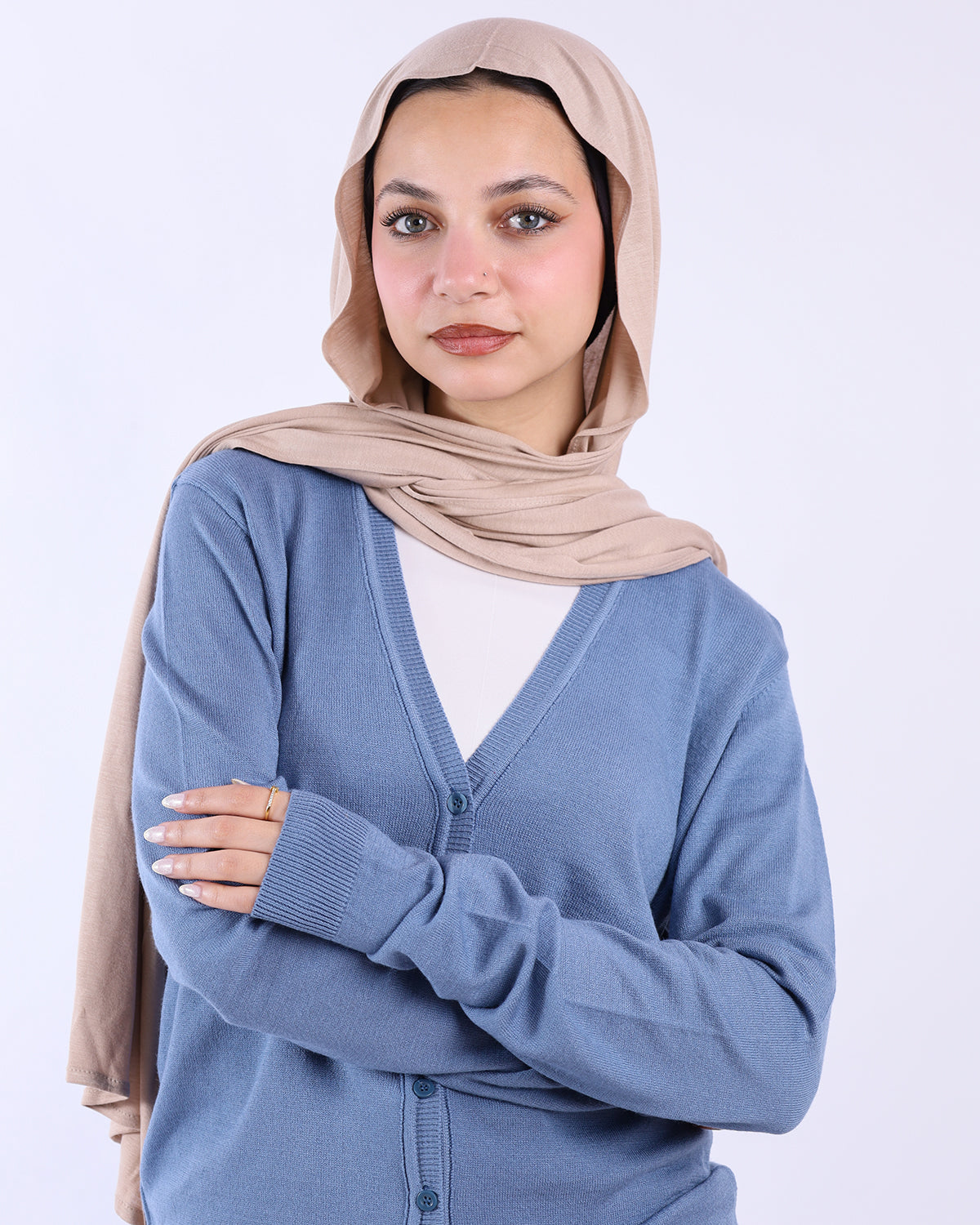 Woman wearing a beige hijab and blue cardigan on a white background- WIND Shopping