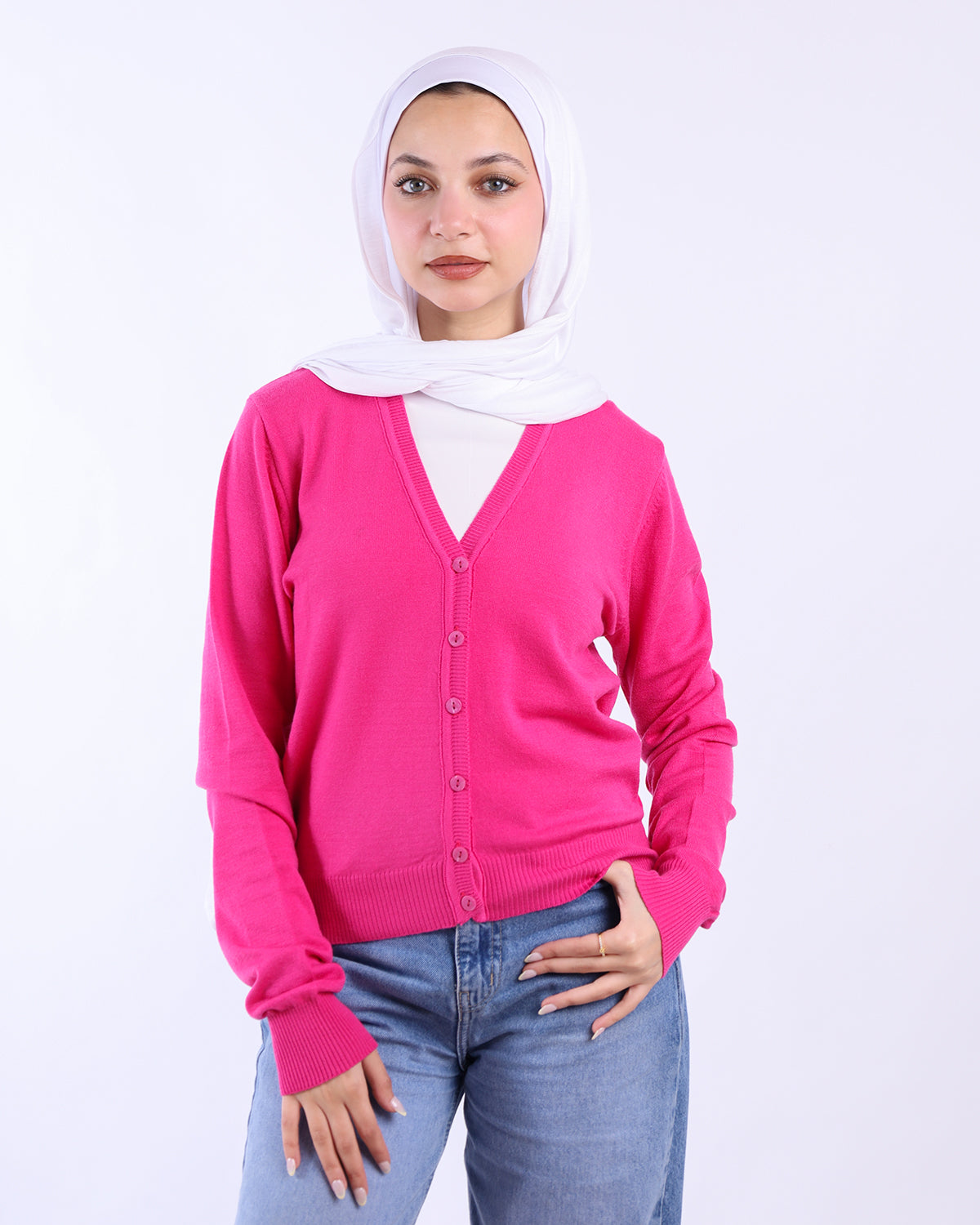 Woman wearing a bright pink cardigan over a white hijab on a light gray background-WIND Shopping