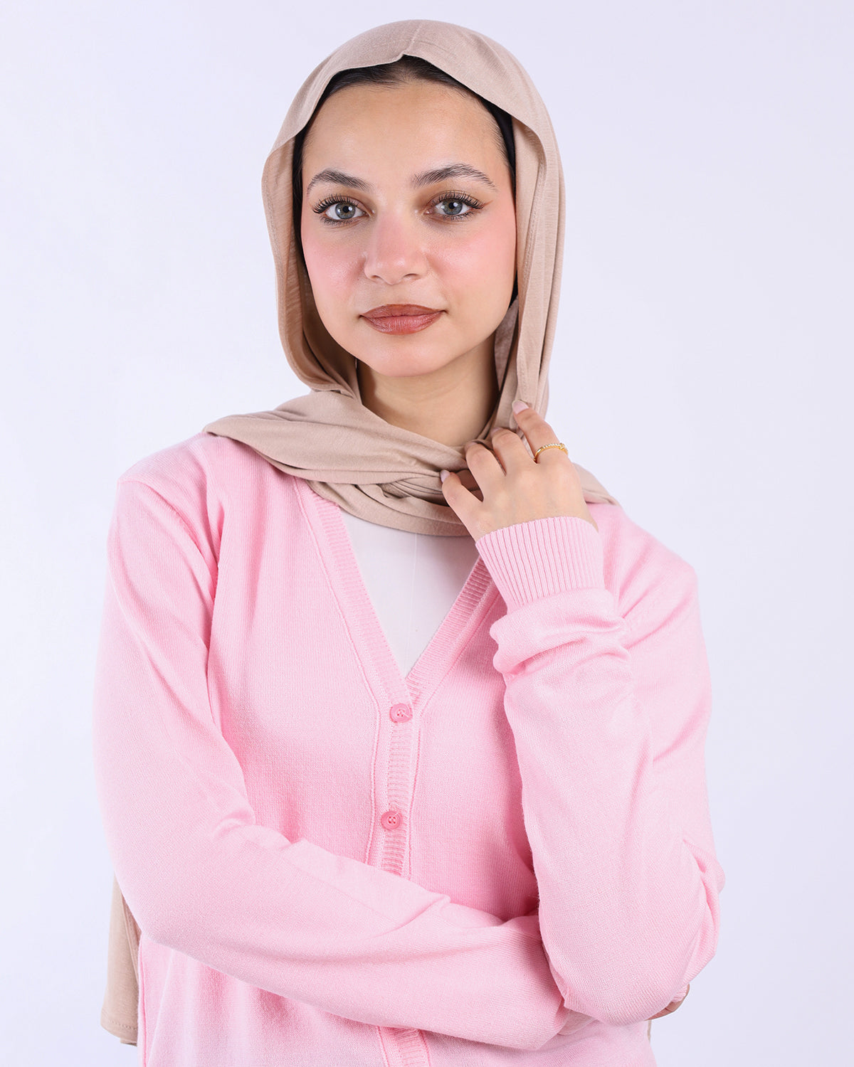 Woman wearing a beige hijab and pink cardigan on a white background- WIND Shopping