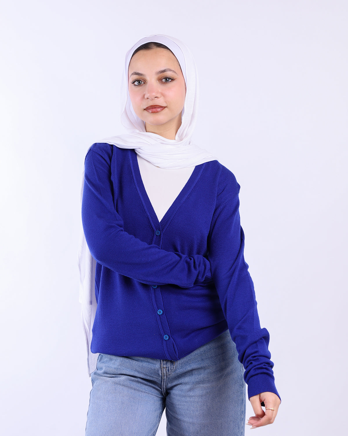 Woman wearing a blue cardigan, white shirt, and light blue jeans on a white background- WIND Shopping