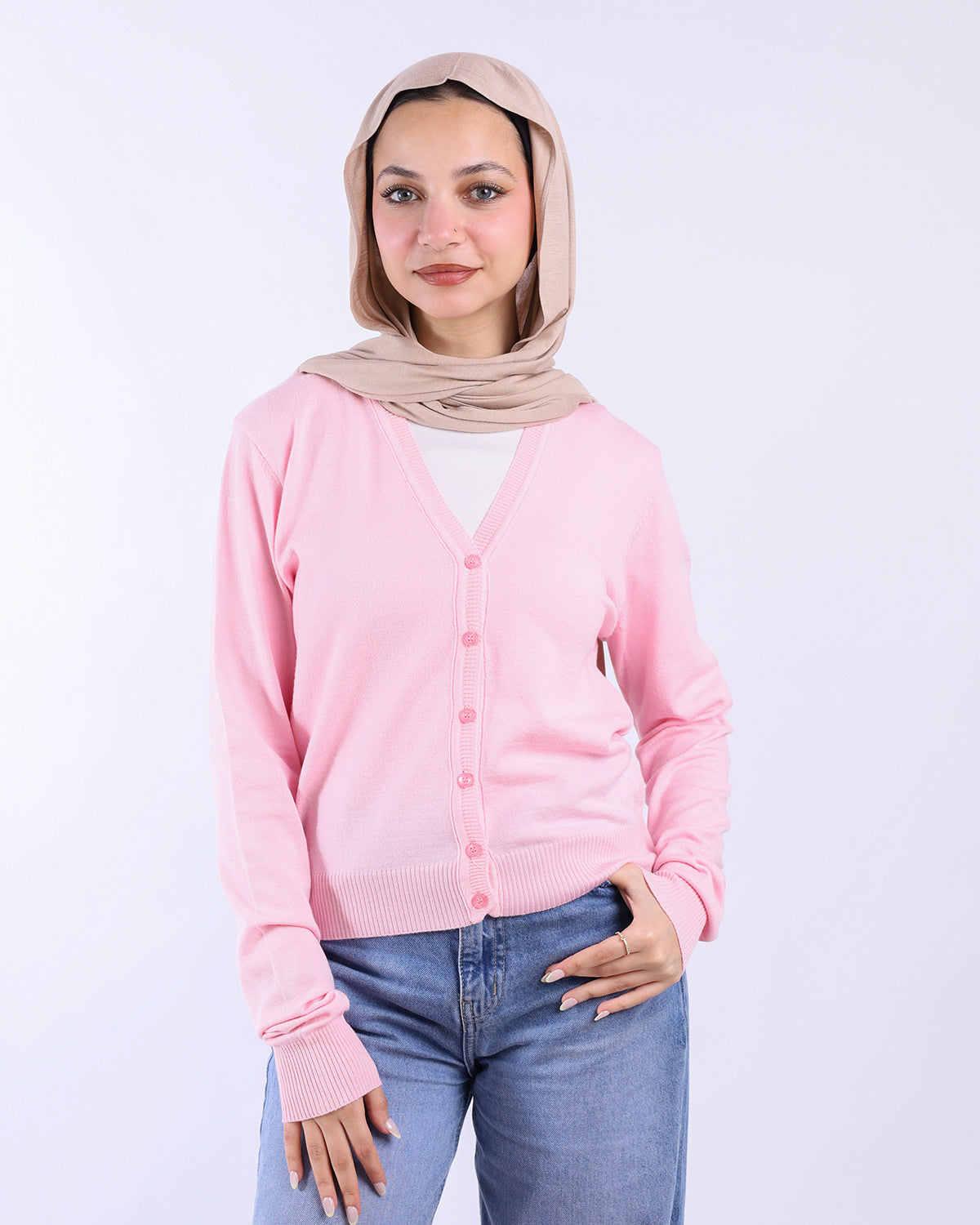 Woman wearing a pink cardigan and beige hijab on a white background- WIND Shopping