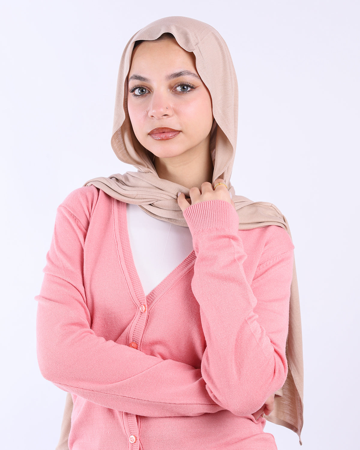 Woman wearing a pink cardigan with a beige hijab on a white background- WIND Shopping