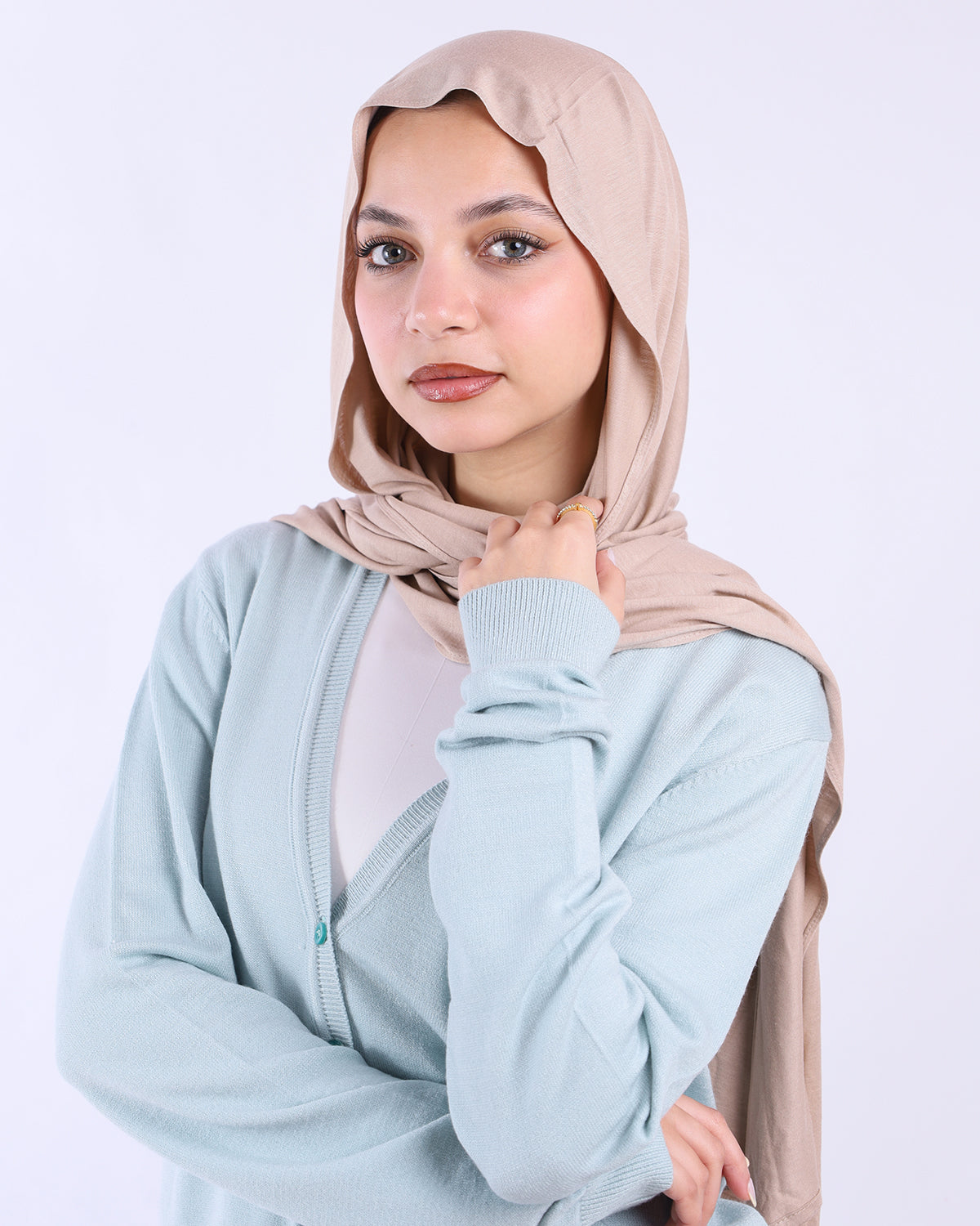 Woman wearing a light blue jacket and beige hijab on a white background- WIND Shopping