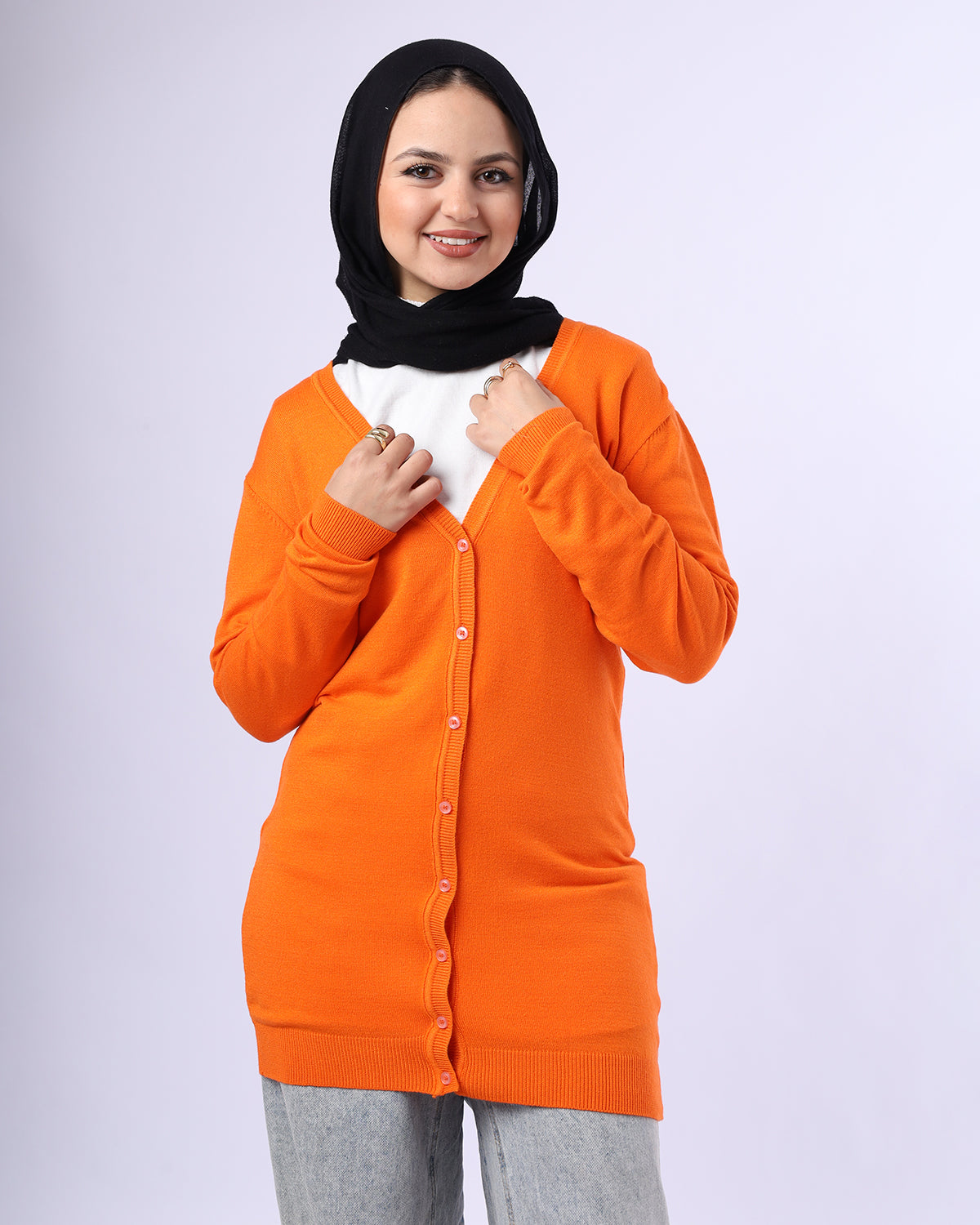 Woman wearing an orange cardigan over a white shirt on a light gray background- WIND Shopping