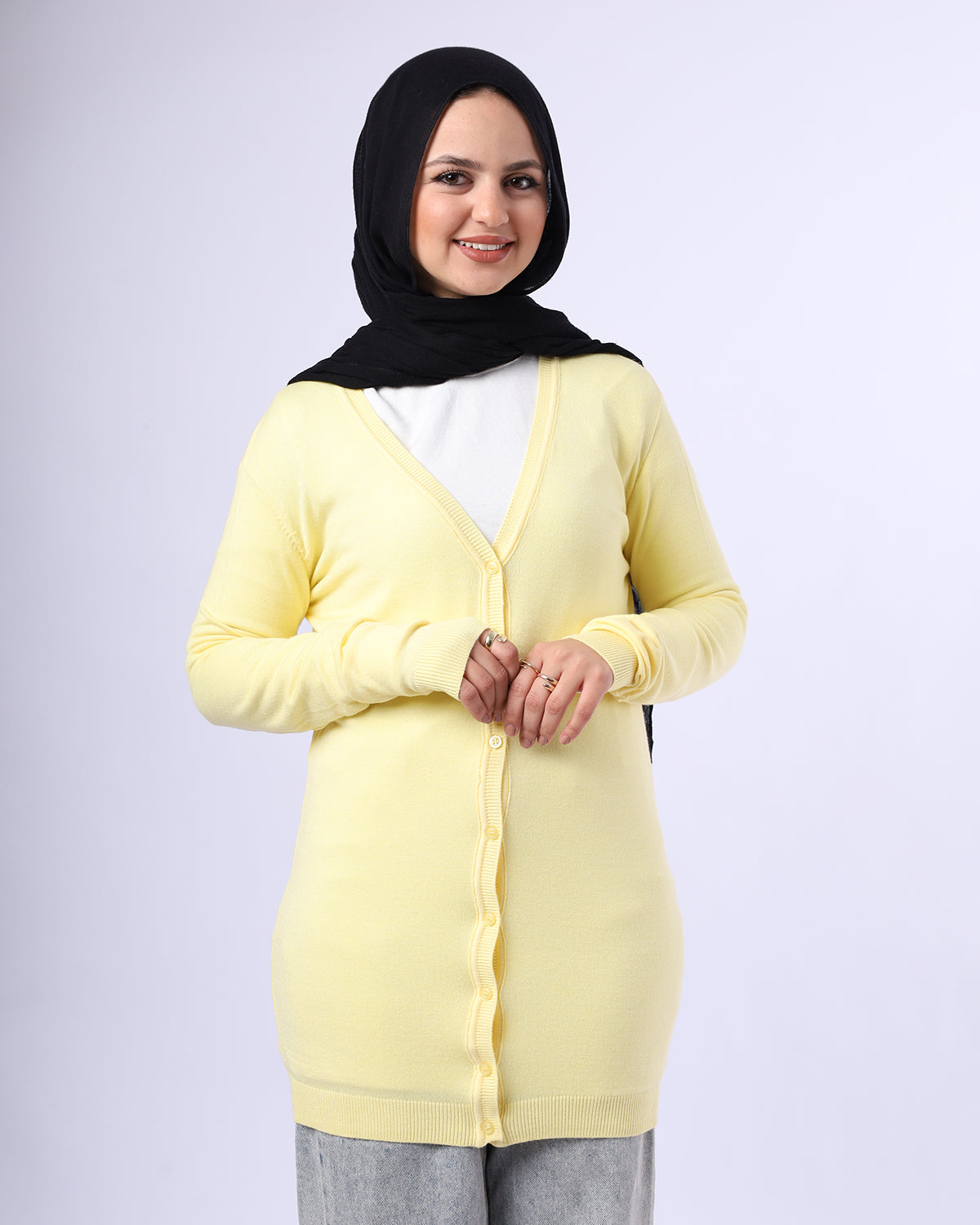 Woman wearing a yellow cardigan over a white shirt with a black hijab on a light gray background- WIND Shopping
