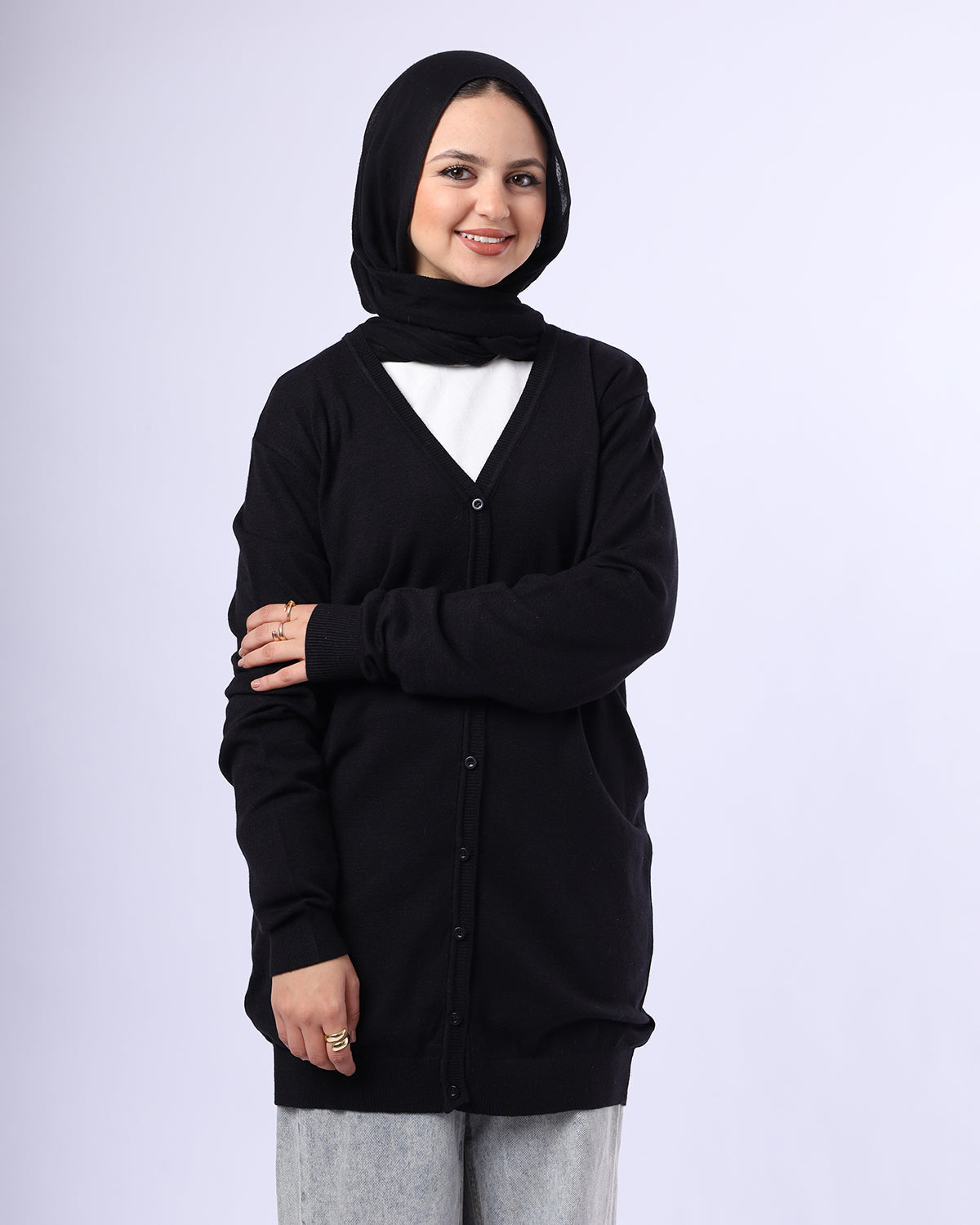 Woman wearing a black cardigan over a white shirt with a hijab on a light gray background- WIND Shopping